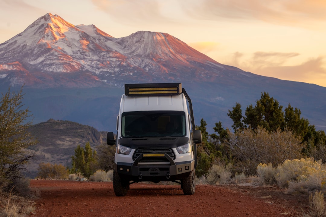 a van parked on a dirt road with a mountain in the background