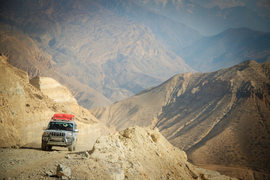 A jeep drives on a mountain road with scenic views.
