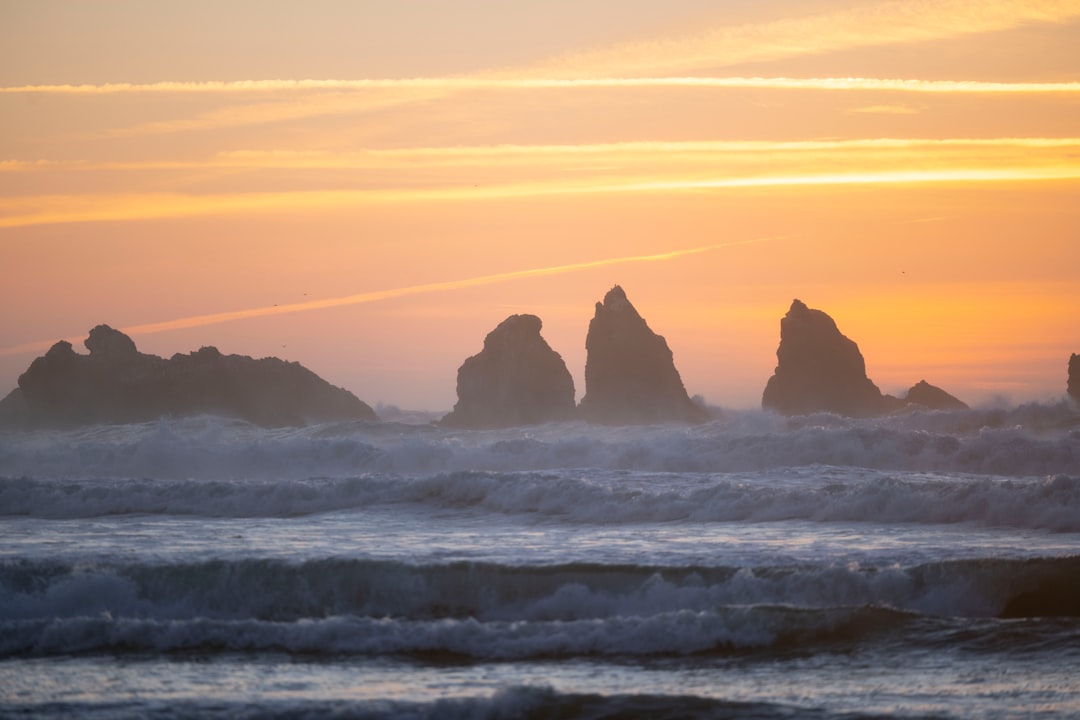 a group of rocks in the ocean at sunset